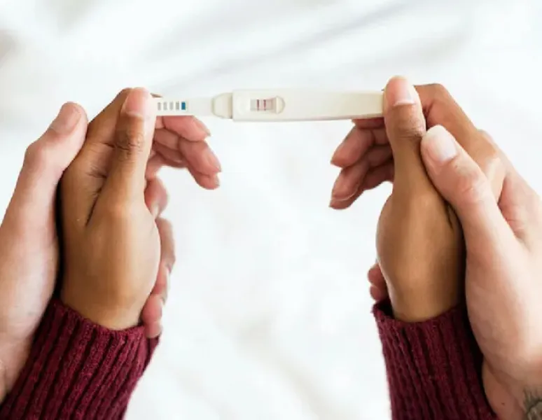 Woman's & man's hands holding a positive pregnancy test.