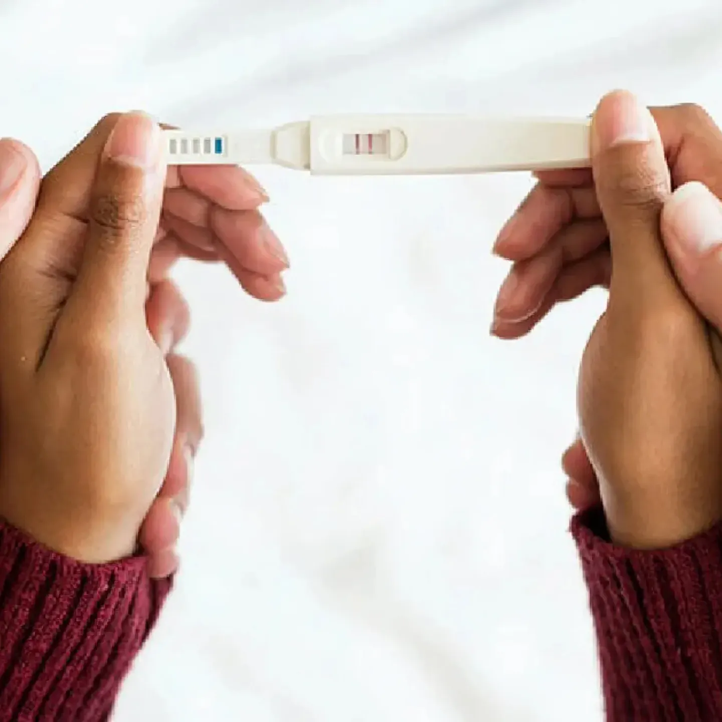 Woman's & man's hands holding a positive pregnancy test.