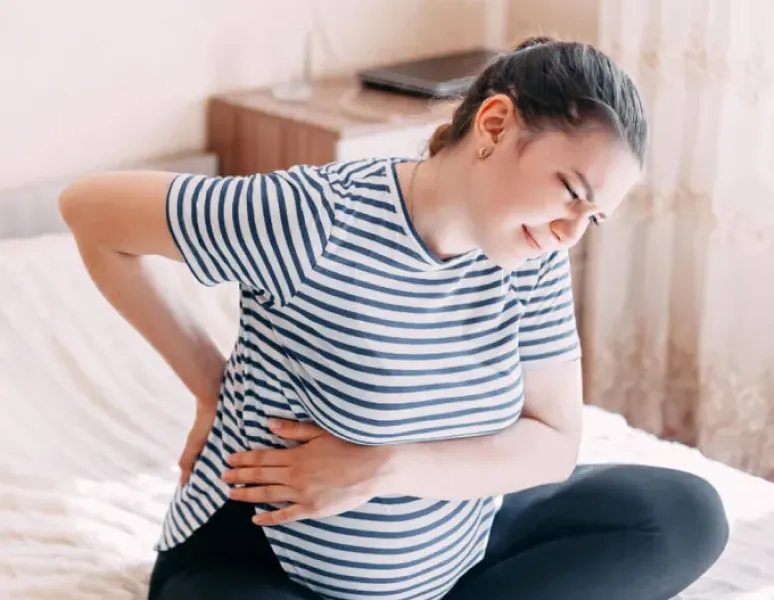Pregnant woman sitting and feeling back pain.