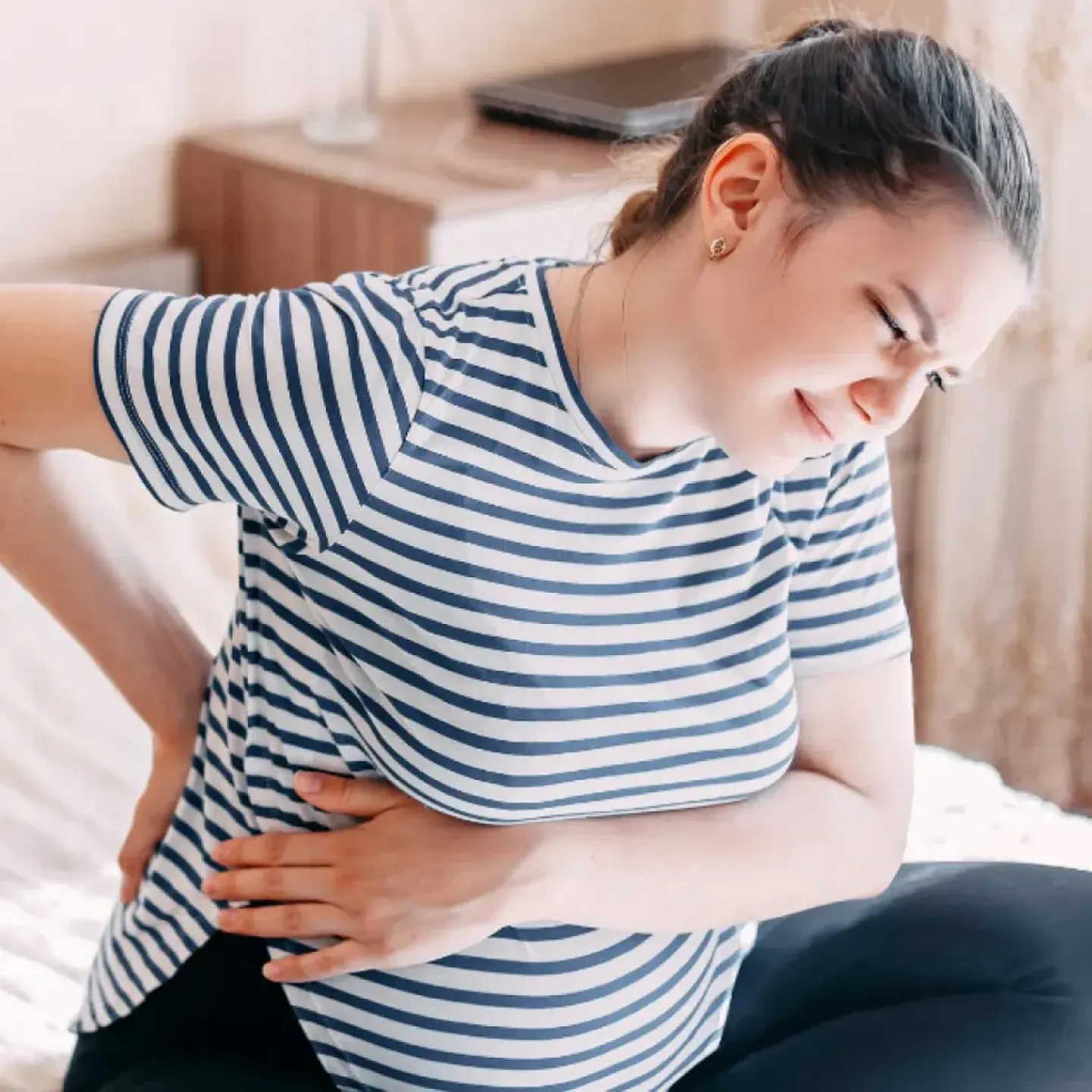 Pregnant woman sitting and feeling back pain.