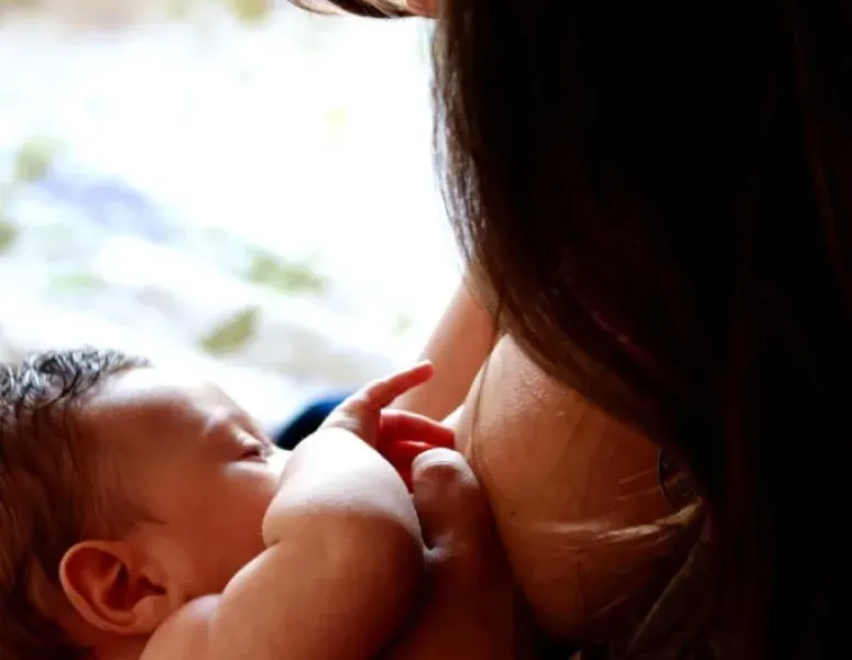 Woman breastfeeding while reducing shoulder, back, neck & wrist pain.