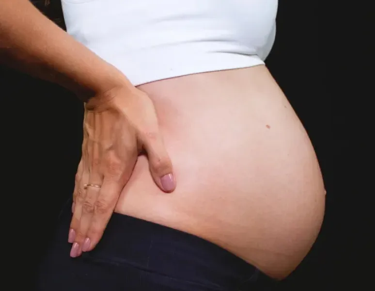 A pregnant woman in pain holding her back.