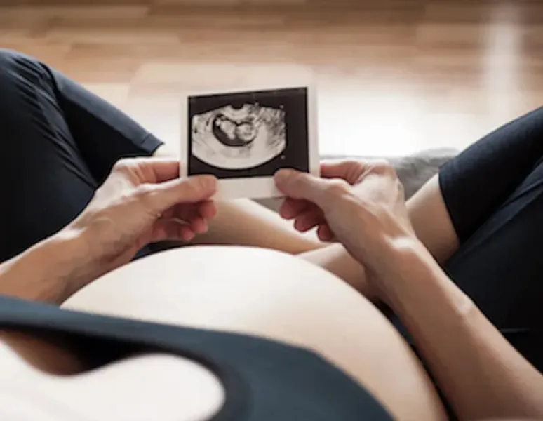 A pregnant woman looking at an ultrasound image and worrying about gestational diabetes.