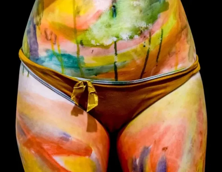 The midsection of a female body painted in beautiful colors to represent the sacral chakra and pelvic floor.