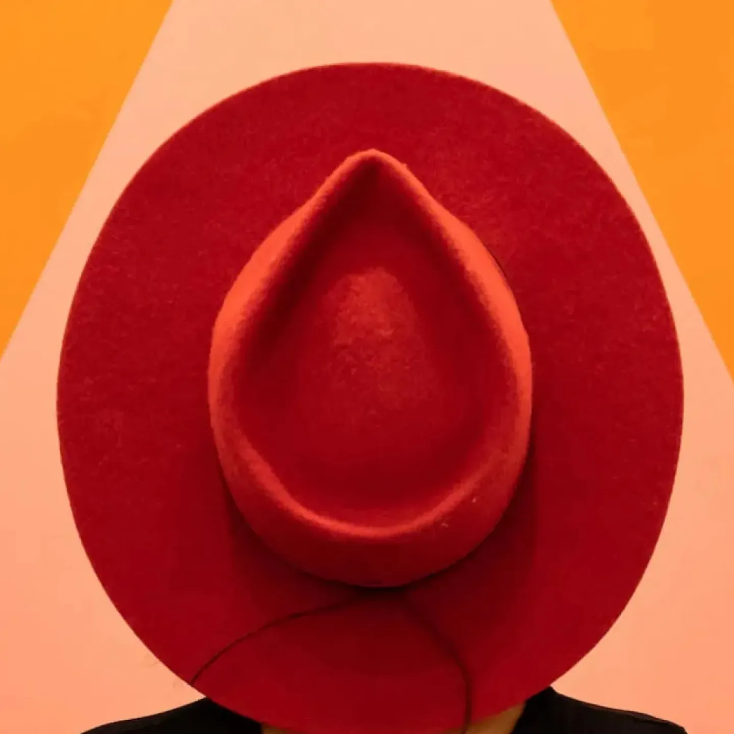 A photo of a woman wearing a red hat in front of a big triangle to symbolize vaginal pain.