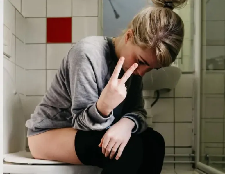 A woman sitting on the toilet, frustrated about her overactive bladder.