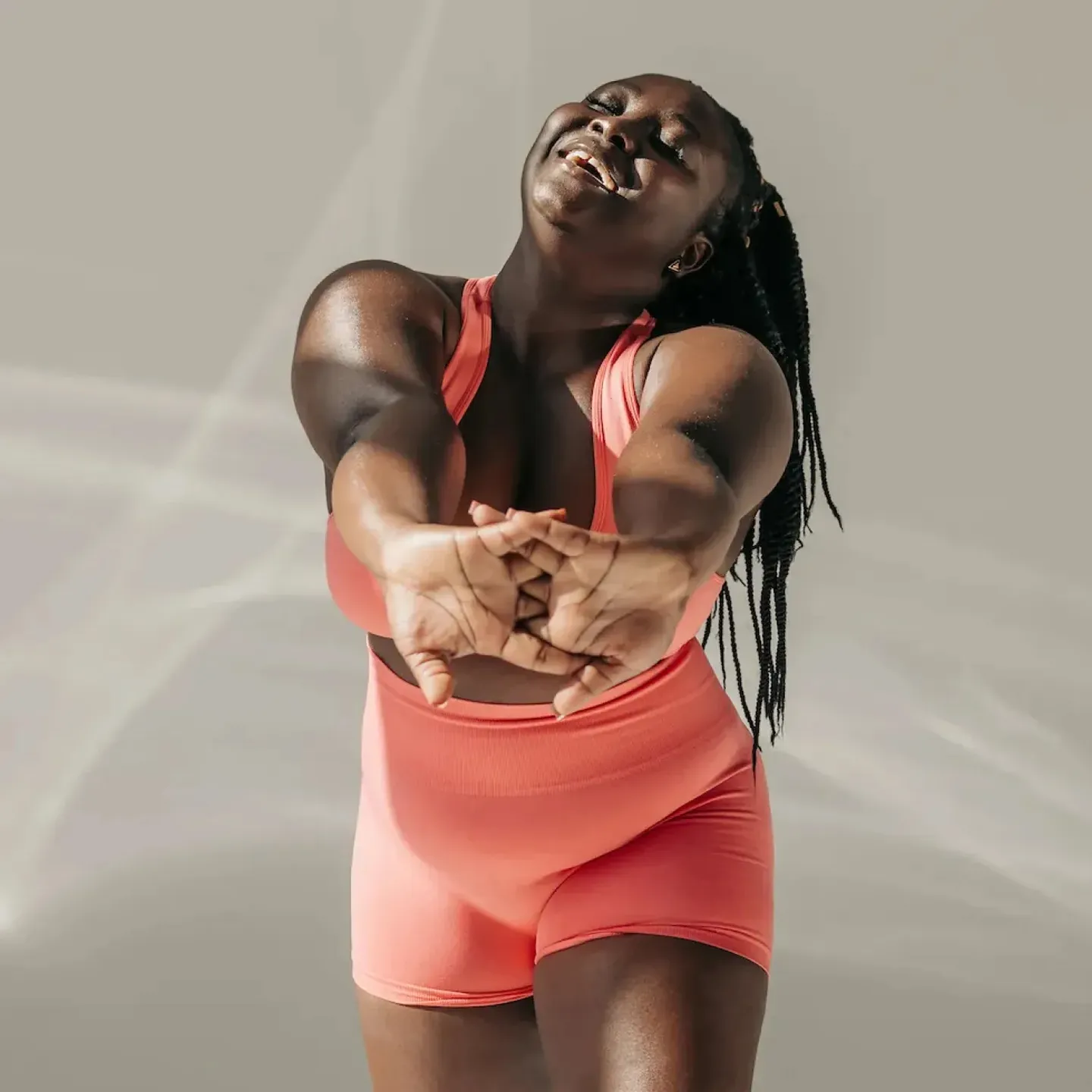 A woman with a round, soft belly smiling and stretching her arms.