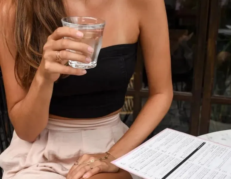 Woman drinking water in a restaurant.
