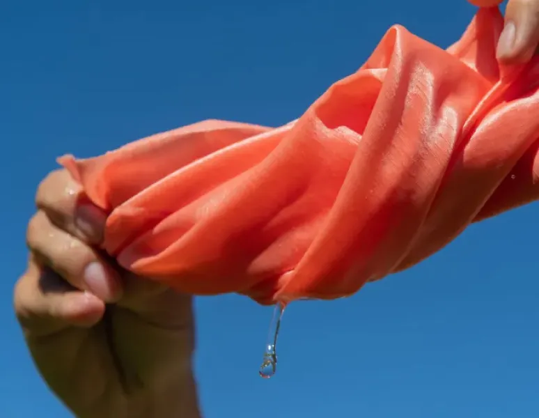 A woman wringing water out of a pink cloth.