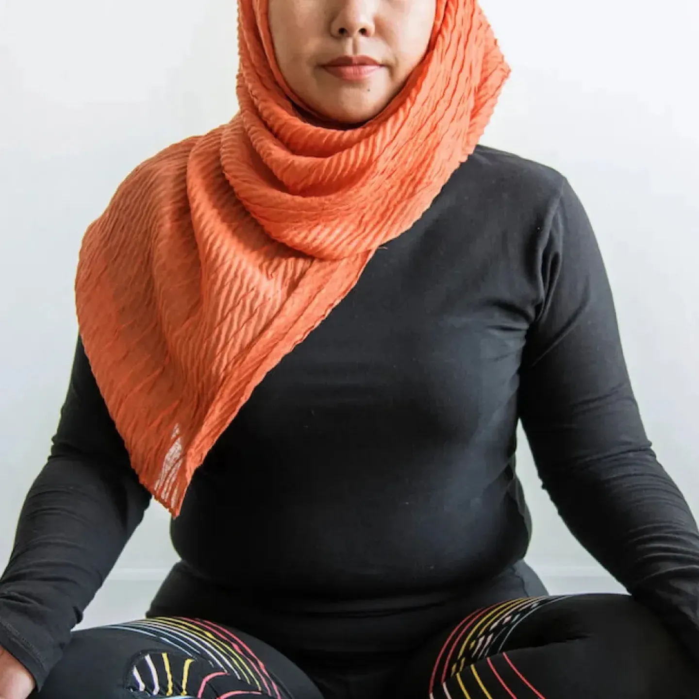 An Islamic woman meditating on a yoga mat.