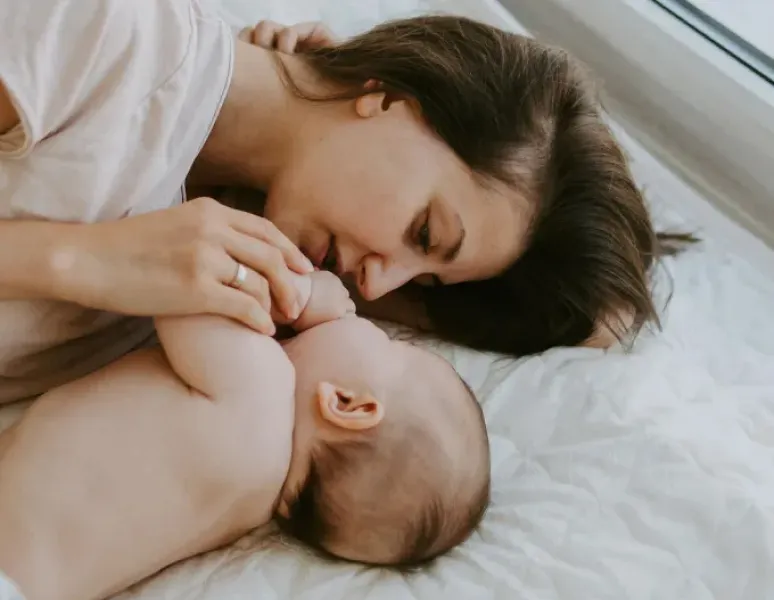 A mother lying face to face with her adorable baby in bed.
