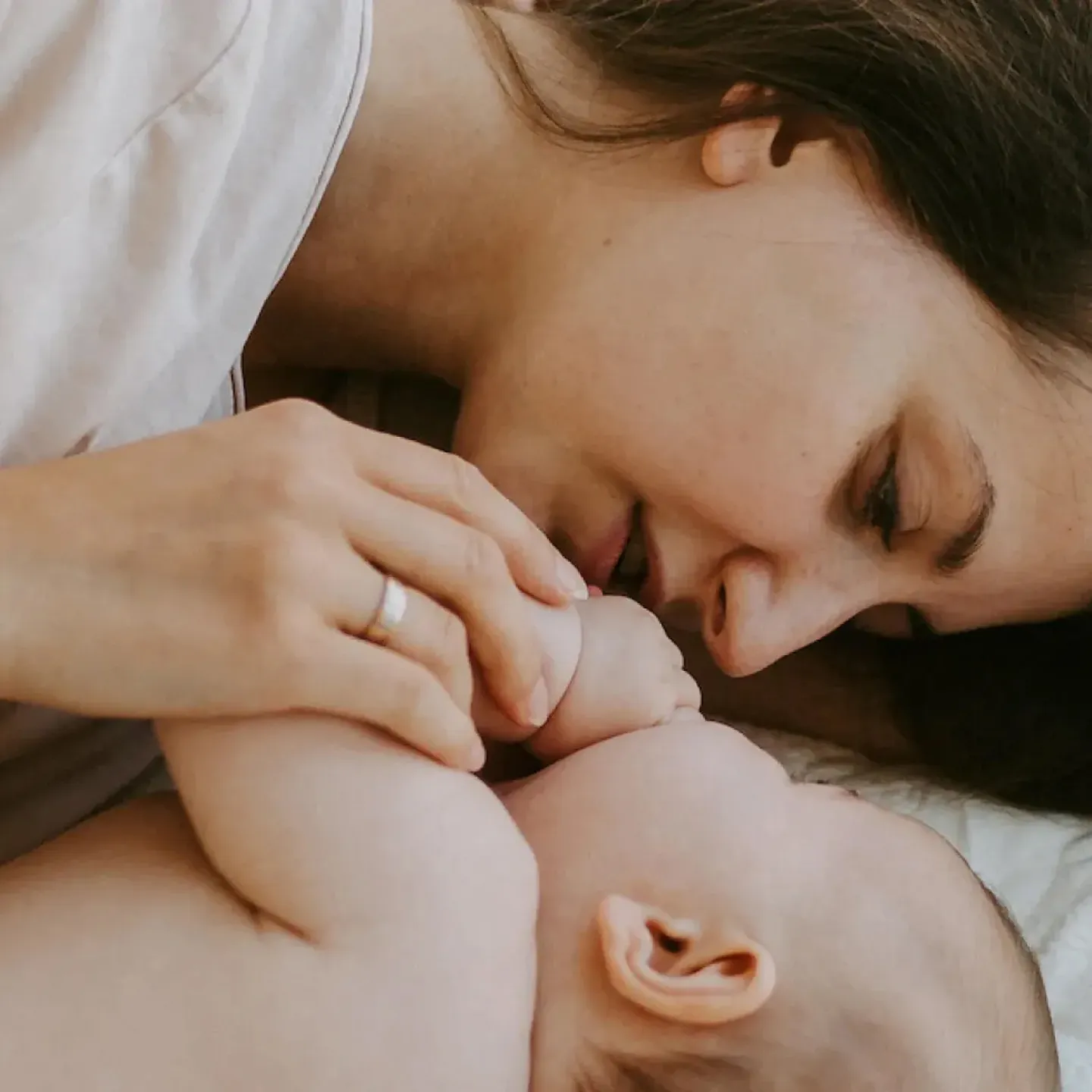 A mother lying face to face with her adorable baby in bed.