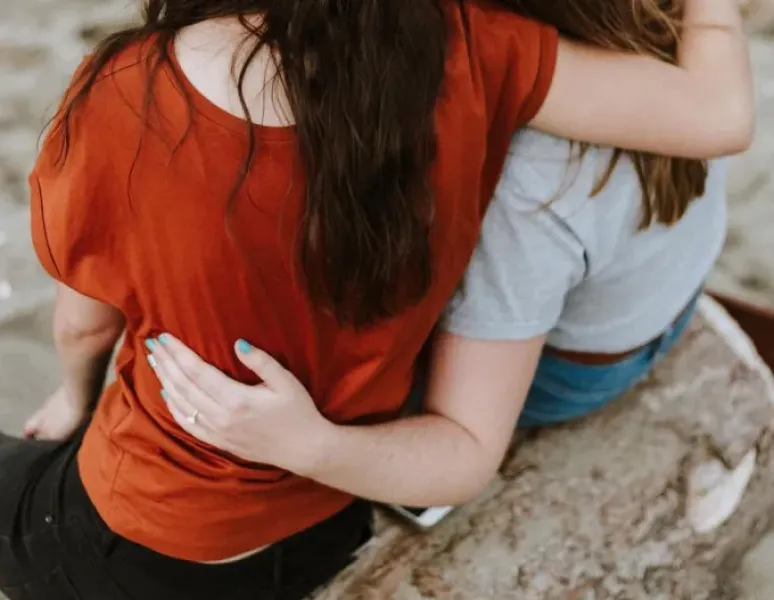 Three women with their arms around each other for support.