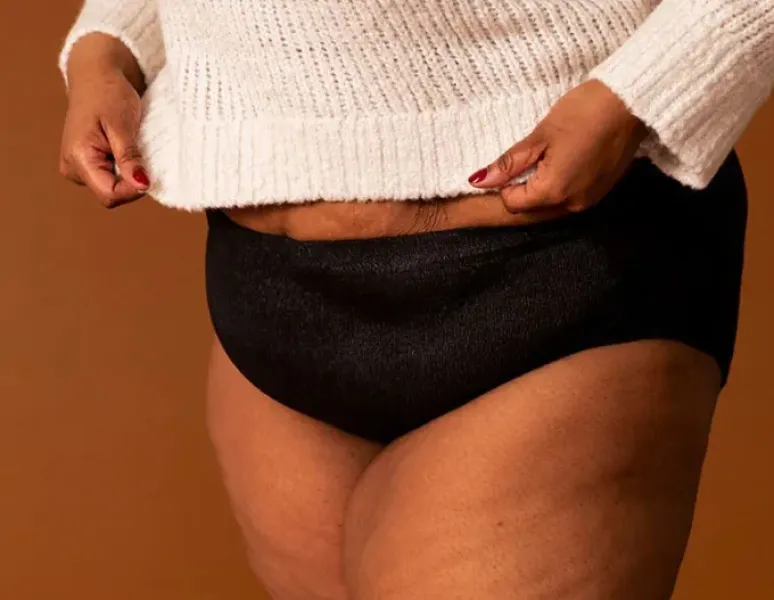 A woman wearing a pair of coral colored absorbant underwear.