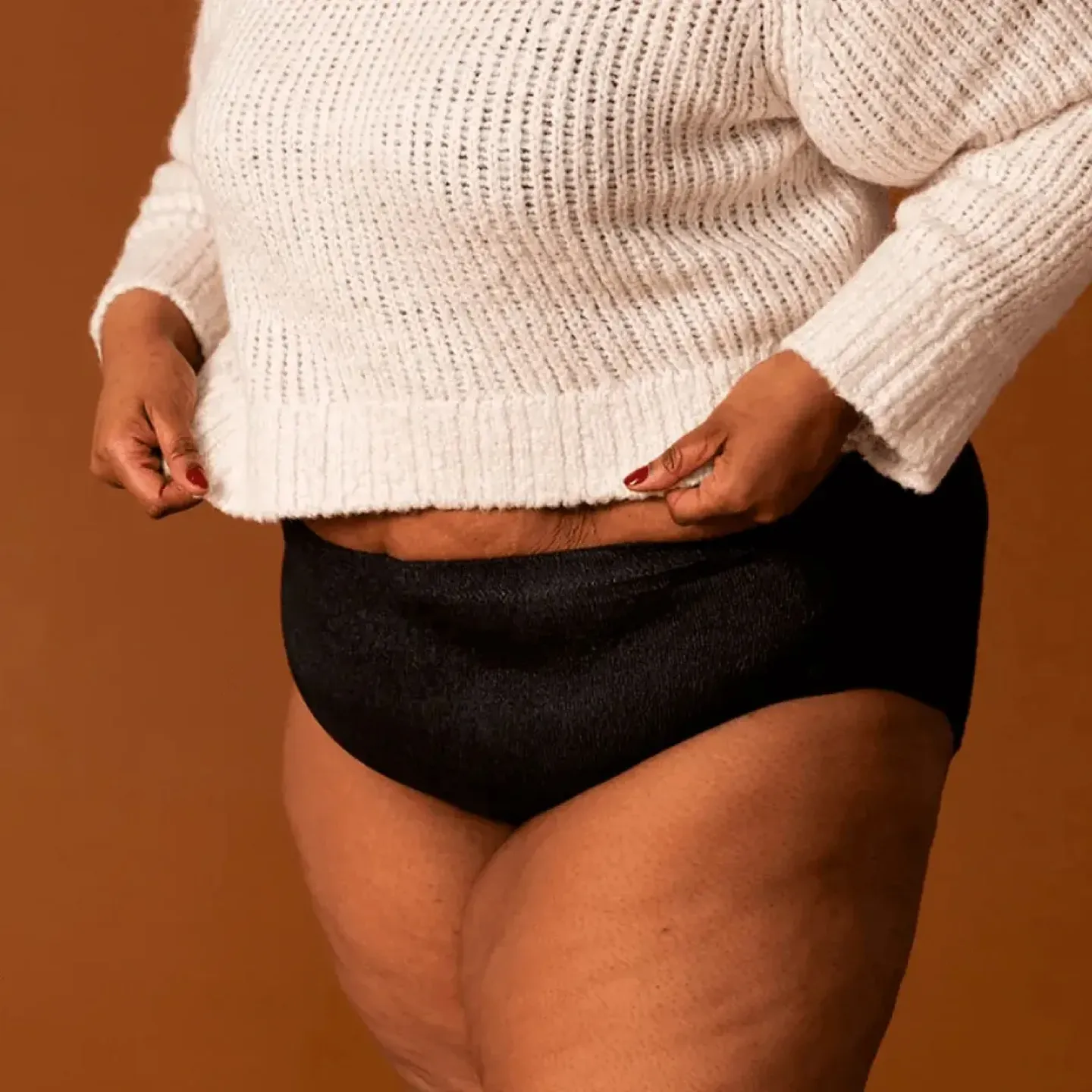 A woman wearing a pair of coral colored absorbant underwear.