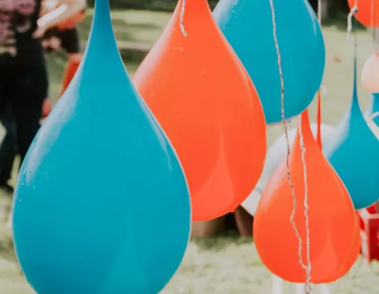 Large blue and red water balloons hanging from a line.