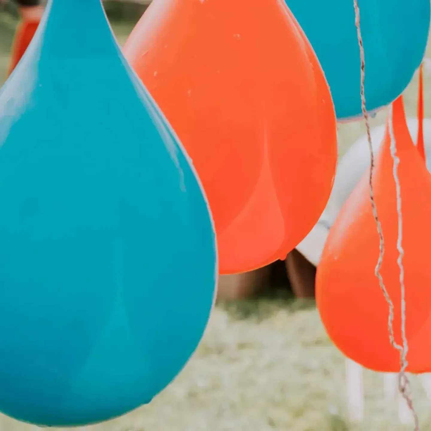 Large blue and red water balloons hanging from a line.