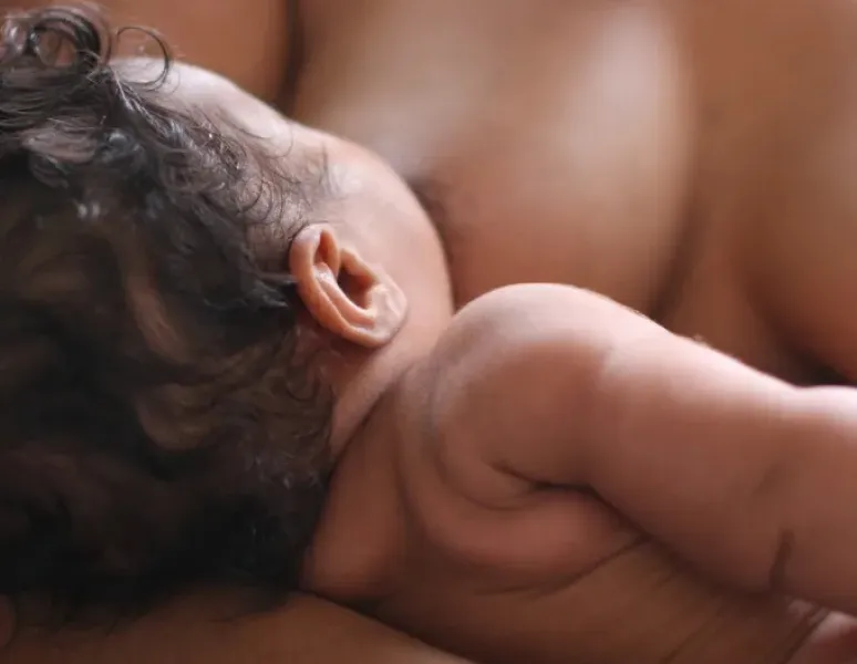 A postpartum individual breastfeeding their newborn.