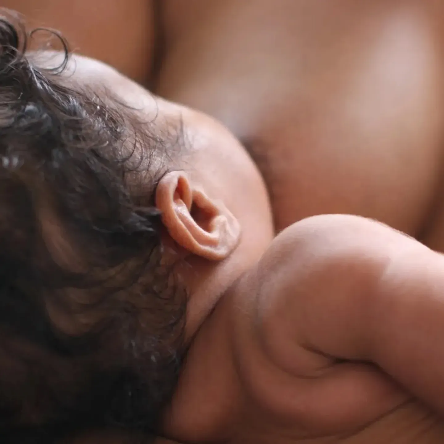 A postpartum individual breastfeeding their newborn.