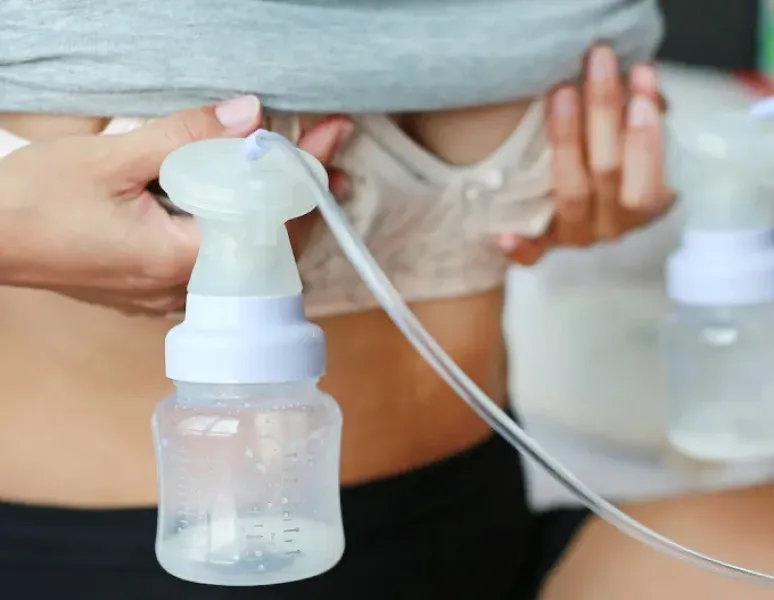 A person pumping while her baby sleeps nearby.
