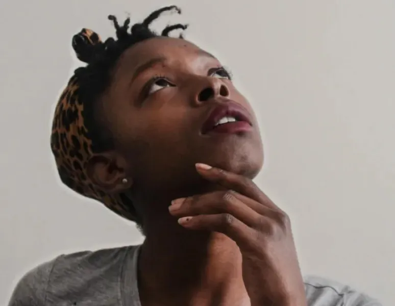 A young woman looking up with her hand on her chin, showing curiosity about her pelvic floor exam.