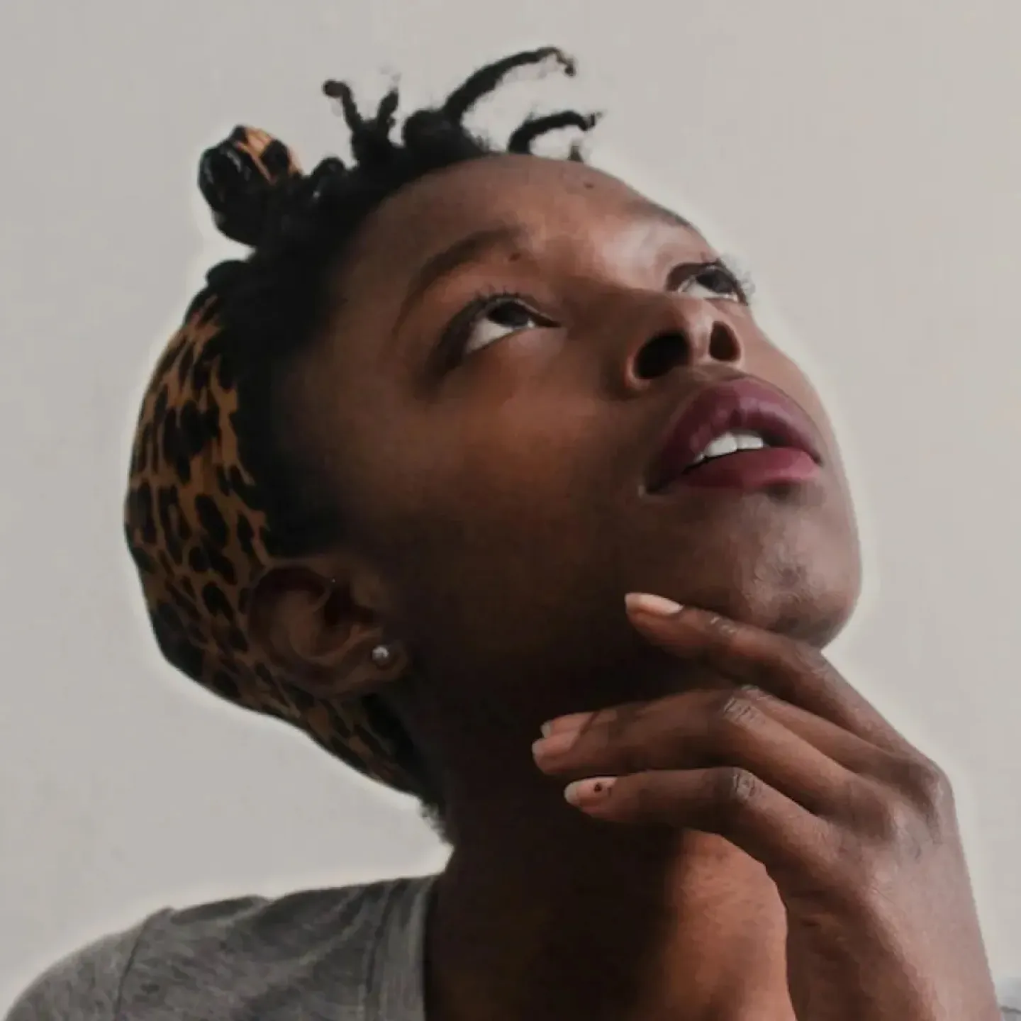 A young woman looking up with her hand on her chin, showing curiosity about her pelvic floor exam.