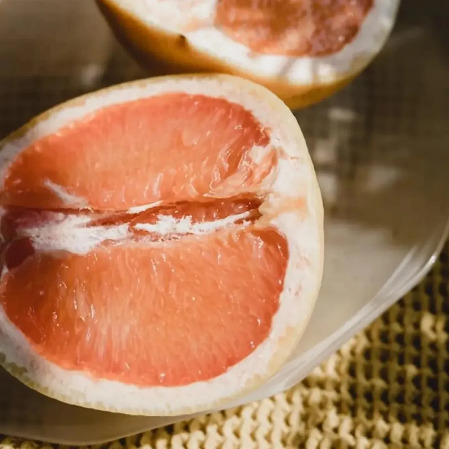 A sliced grapefruit that looks like a vulva on a summer table bathed in dappled sunlight.