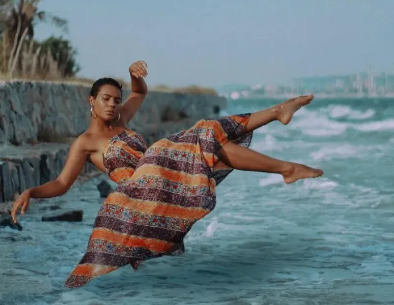 A serene woman floating in the air over the sea in a flowing dress to evoke the subconscious, freedom of feeling, and a mind-body connection.