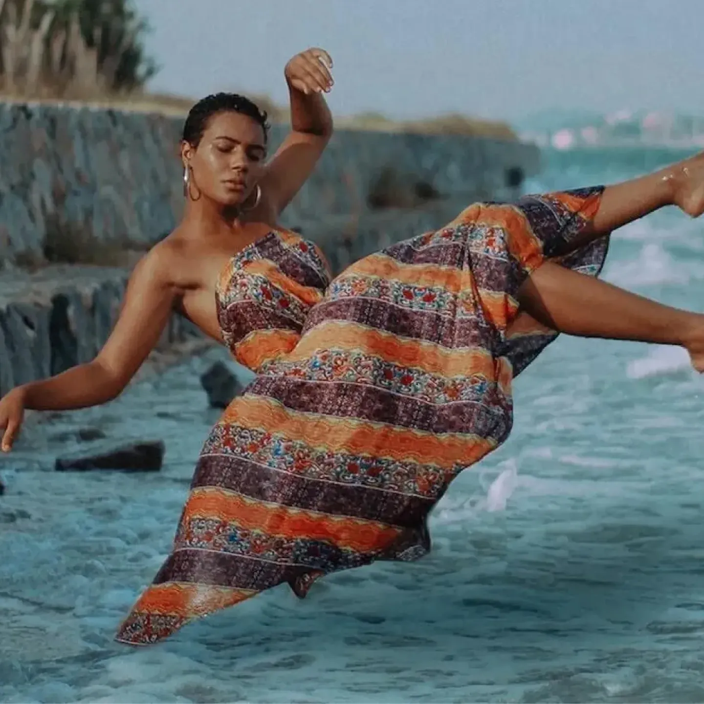 A serene woman floating in the air over the sea in a flowing dress to evoke the subconscious, freedom of feeling, and a mind-body connection.