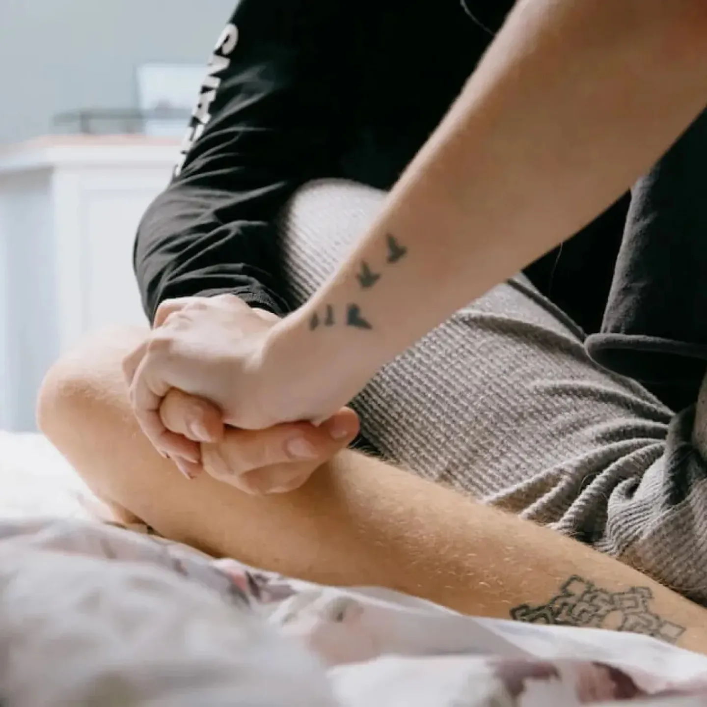A couple sitting on a bed, holding hands.