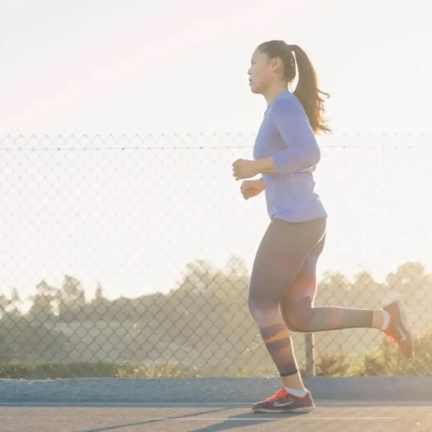 A postpartum woman running at sunset.