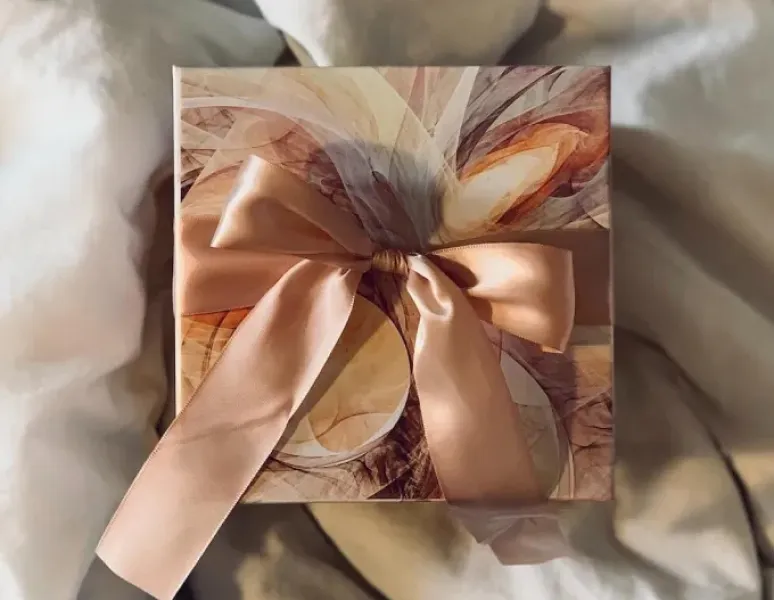 A small, beautifully wrapped gift on a fluffy white duvet cover.