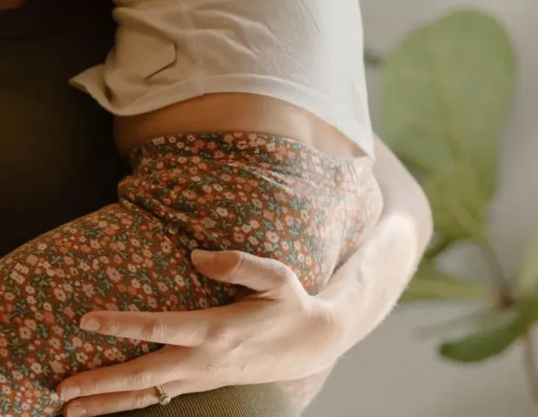 A close-up photo of a woman's hand and wrist holding up her toddler for a story on carpal tunnel syndrome and dequervain's tenosynovitis.