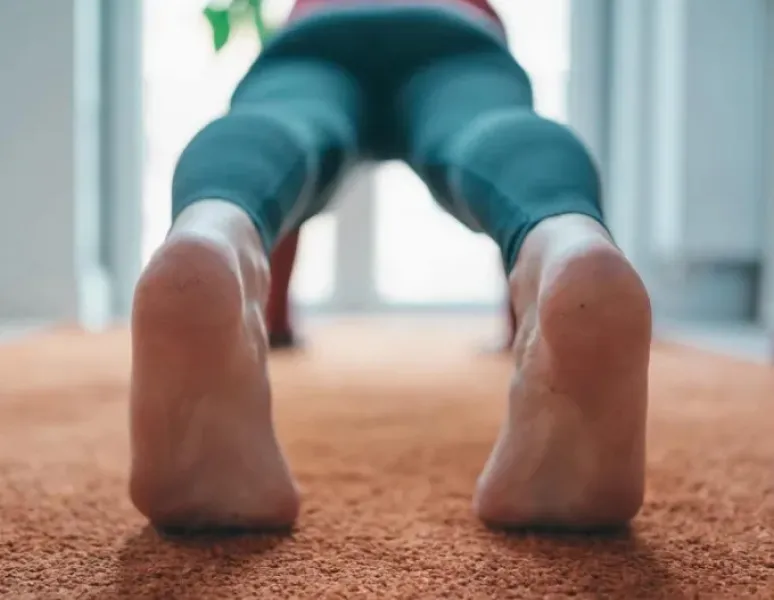 A photo of a woman in plank position, shot from behind to highlight her tight or hypertonic pelvic floor.