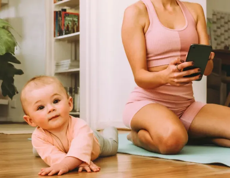 A new mom doing virtual physical therapy at home with her baby.