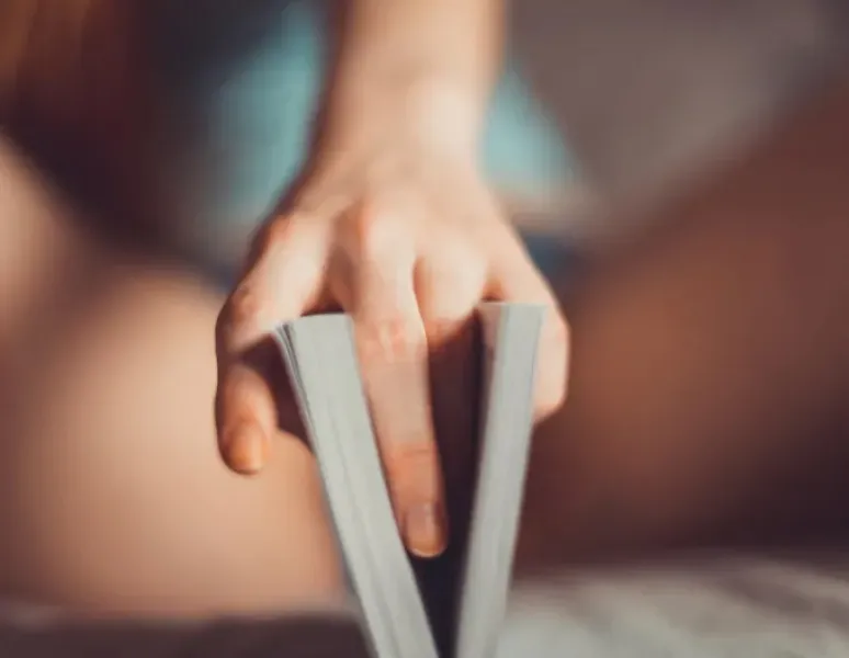 A woman holding a book between her legs to symbolize her vulva and sexuality.