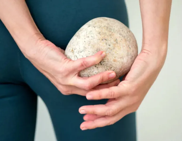A woman holding a large stone behind her body for as story on what pelvic organ prolapse feels like.