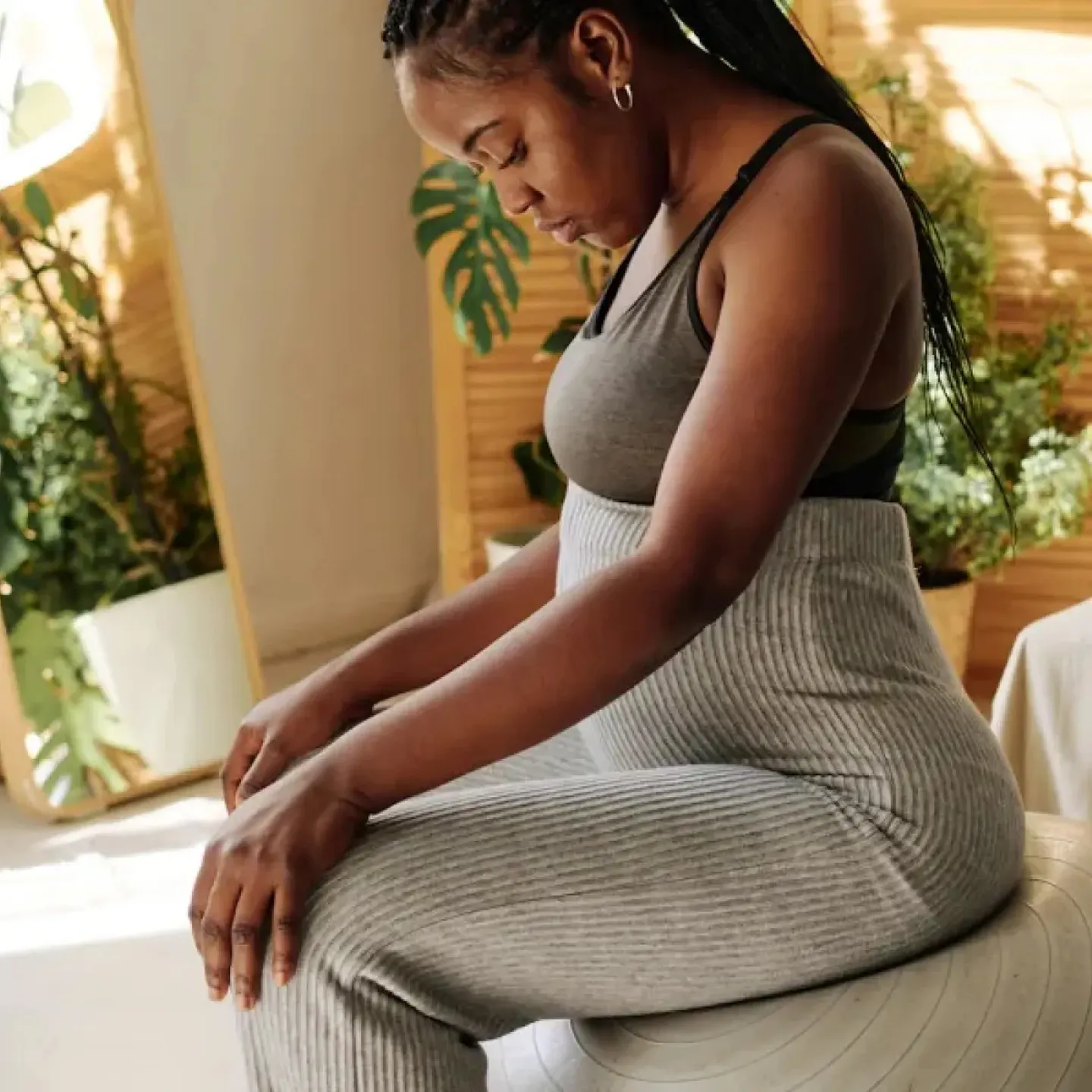 A woman in her second trimester of pregnancy sitting on an exercise ball to relieve her back pain.