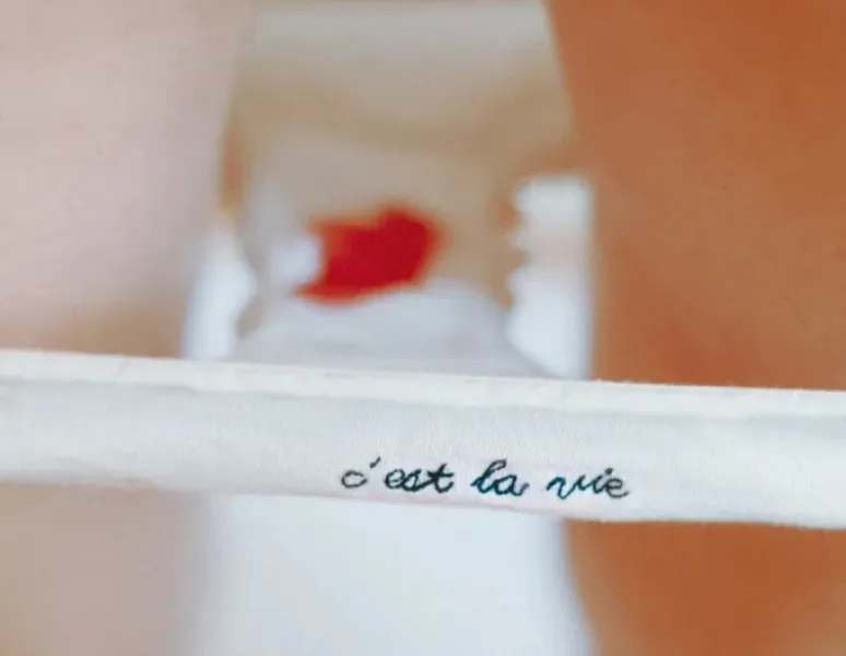 A pair of underwear, stained with period blood, with the words "c'est la vie" embroidered on the front.
