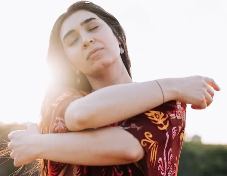 A woman wrapping her arms around herself for a story on pelvic healing after sexual assault.