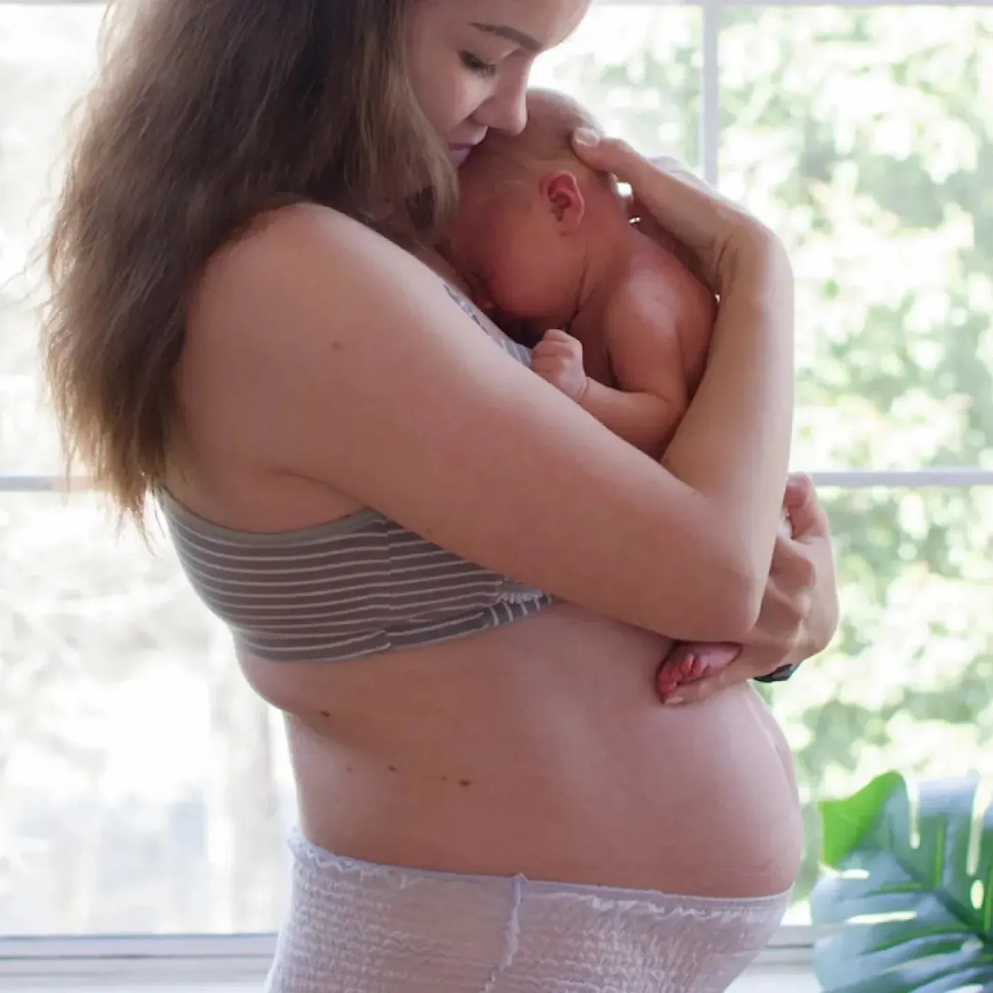 A postpartum mom holding her newborn.