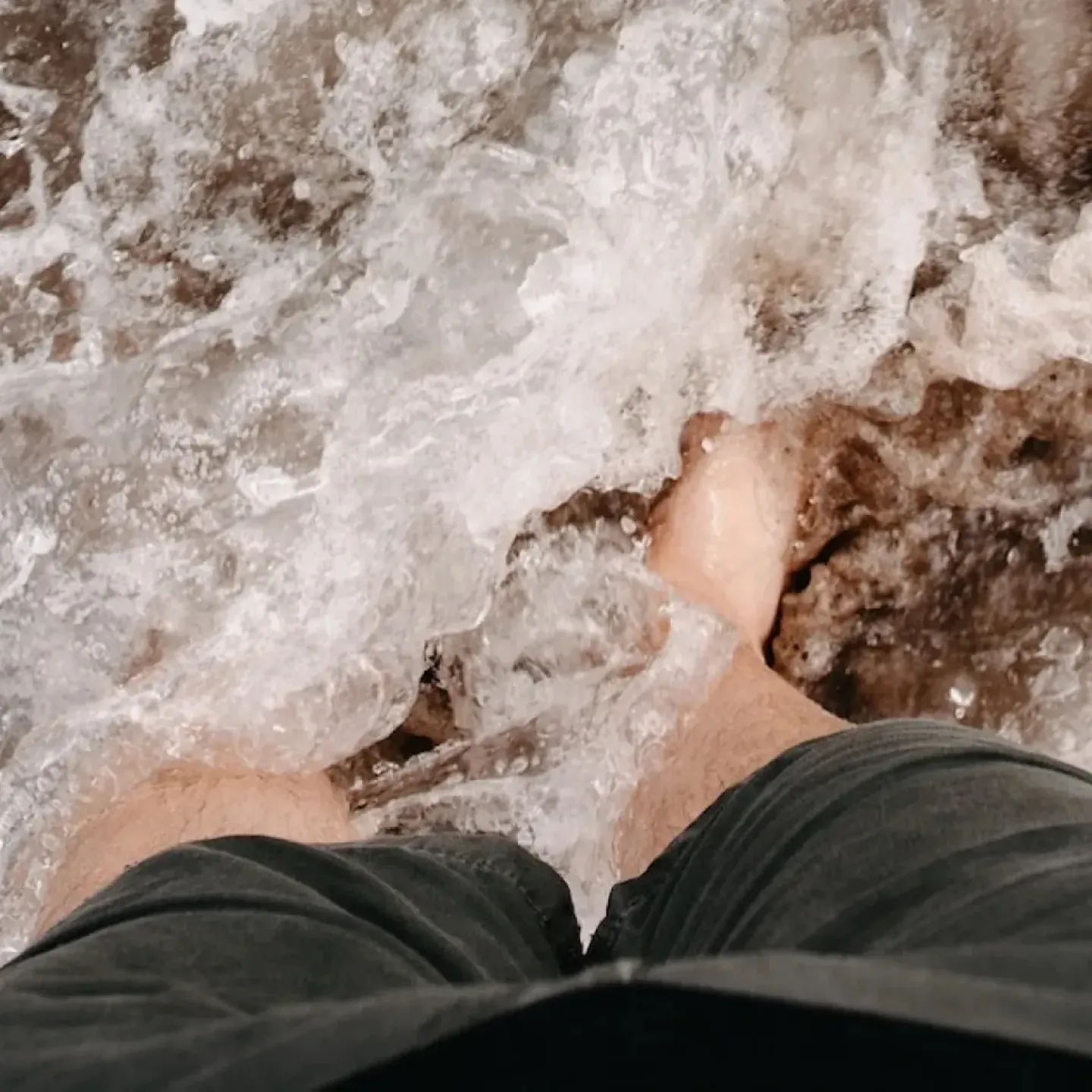 A woman's feet at the edge of the ocean symbolizing the chaotic thoughts that come with postpartum psychosis.