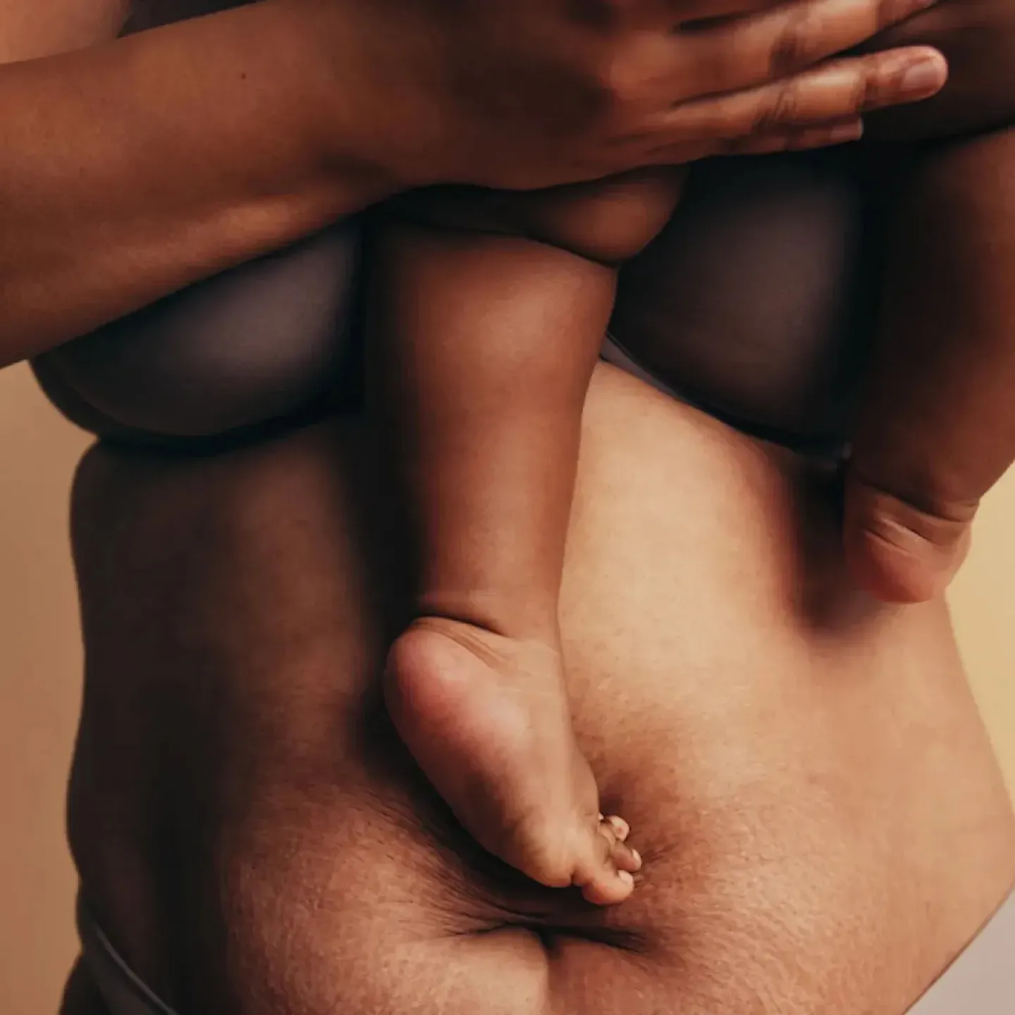 A postpartum birthing person holding her baby before her 6 week postpartum health checkup.