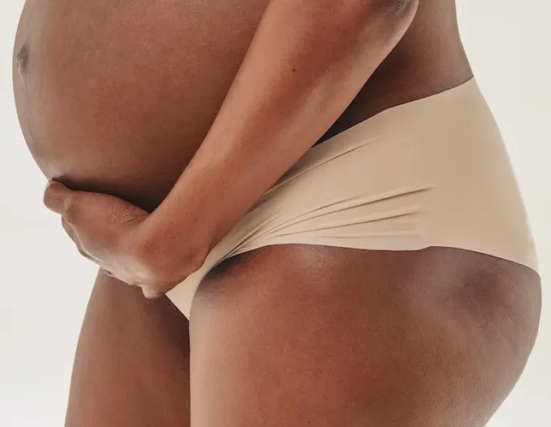 A pregnant woman with pelvic pain lying on a yoga mat at home.