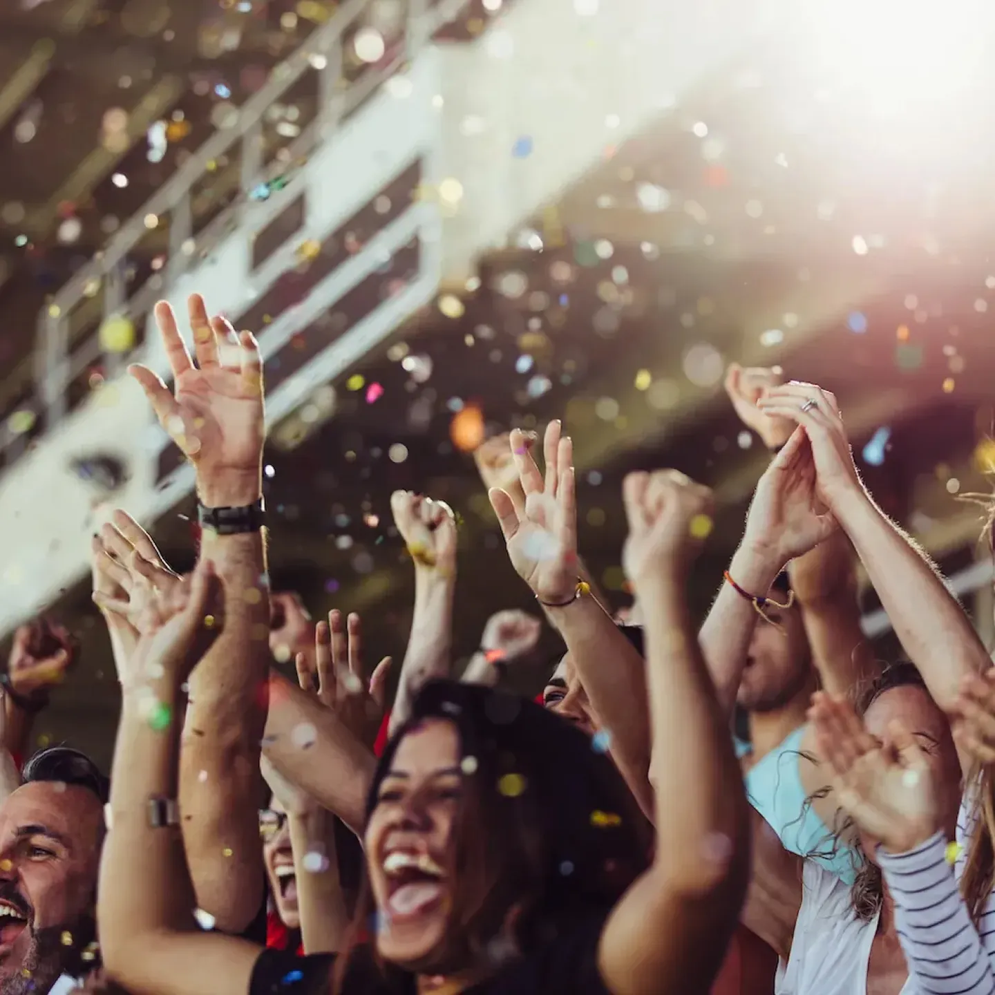 A crowd of women at a stadium cheering with confetti falling from the sky.