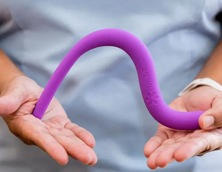 A pelvic floor PT at Origin holding a purple pelvic wand by Intimate Rose.