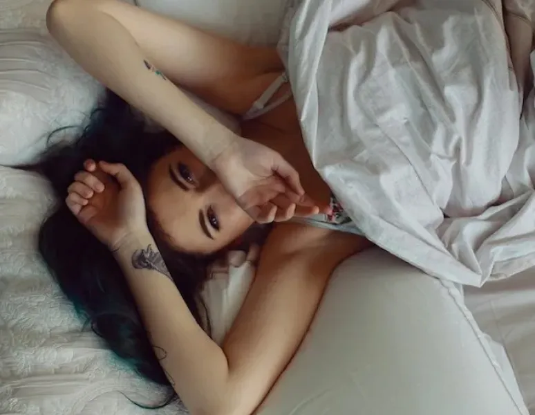 A woman lying in bed upset because she peed during sex.