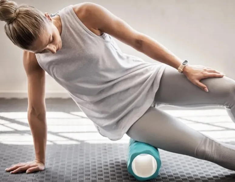 A woman foam rolling her hip in a women's health physical therapy office.