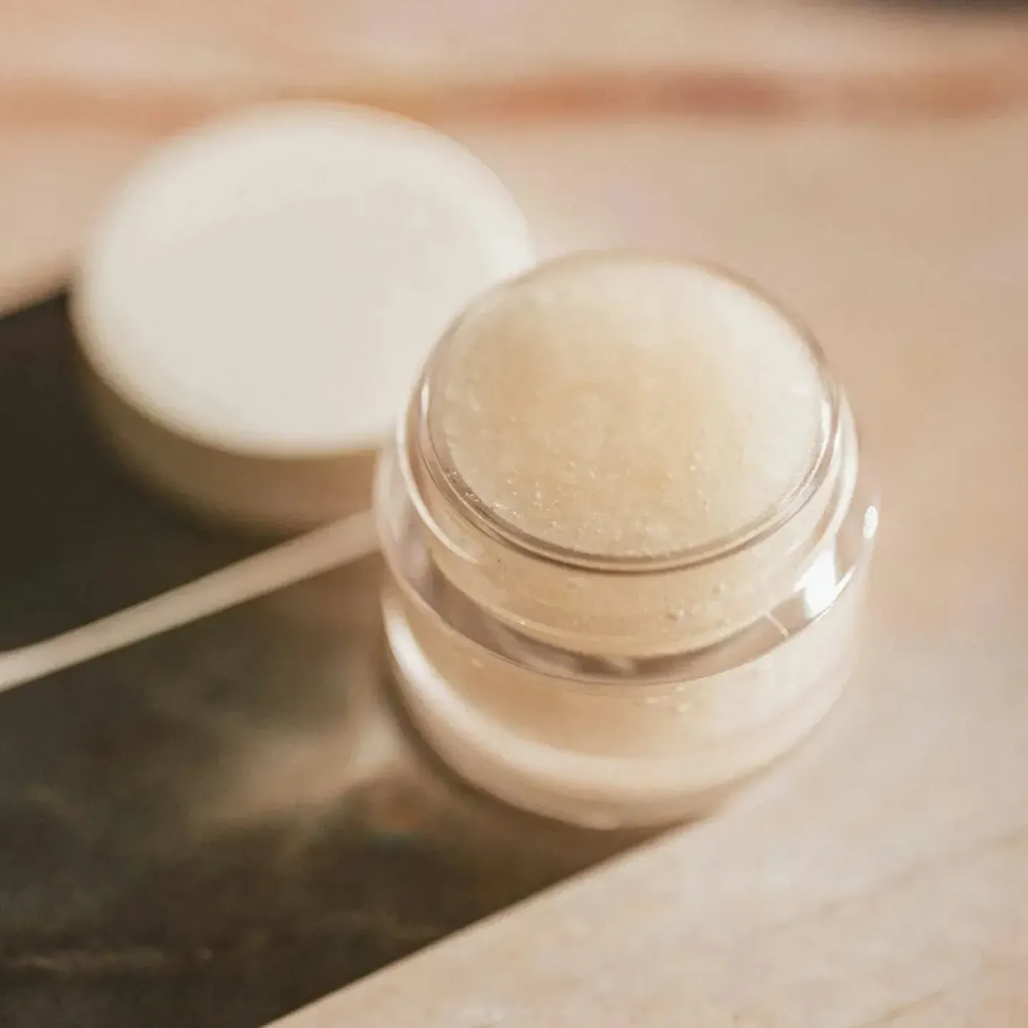 A pot of vulva balm on a marble bathroom counter.