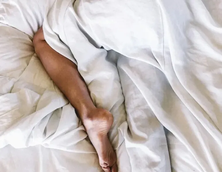 A woman with uterine prolapse lying in bed wondering if it's safe to have sex.